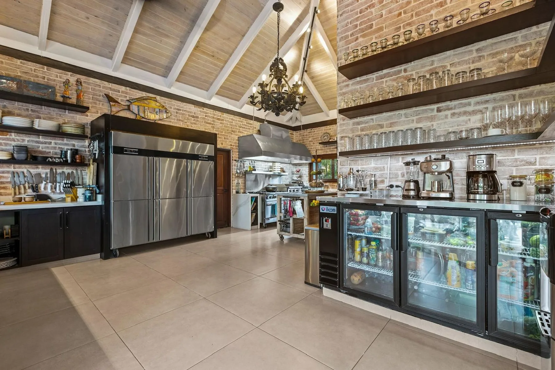 Una cocina comercial y zona de bebidas con refrigeradores bajo estantes de cristalería.