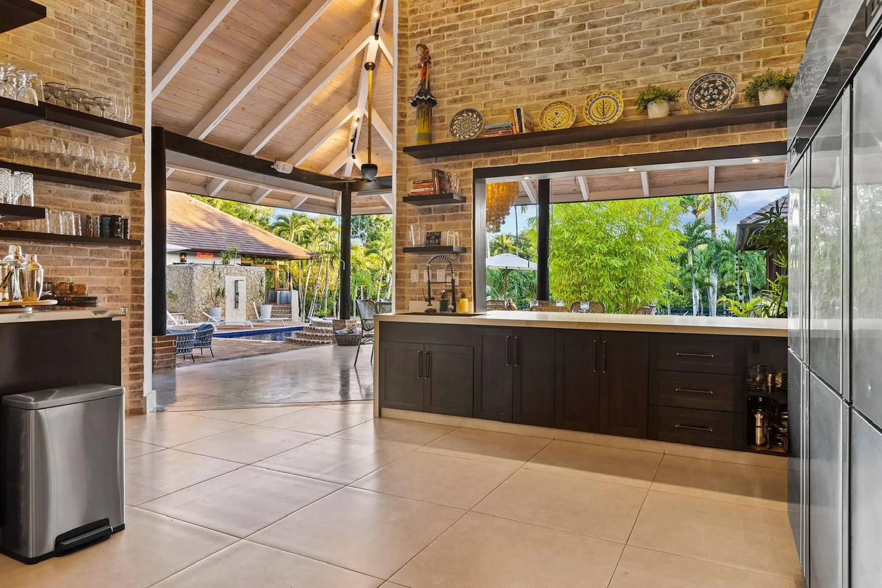 Una cocina con gabinetes oscuros y una amplia ventana con vista a la vegetación.