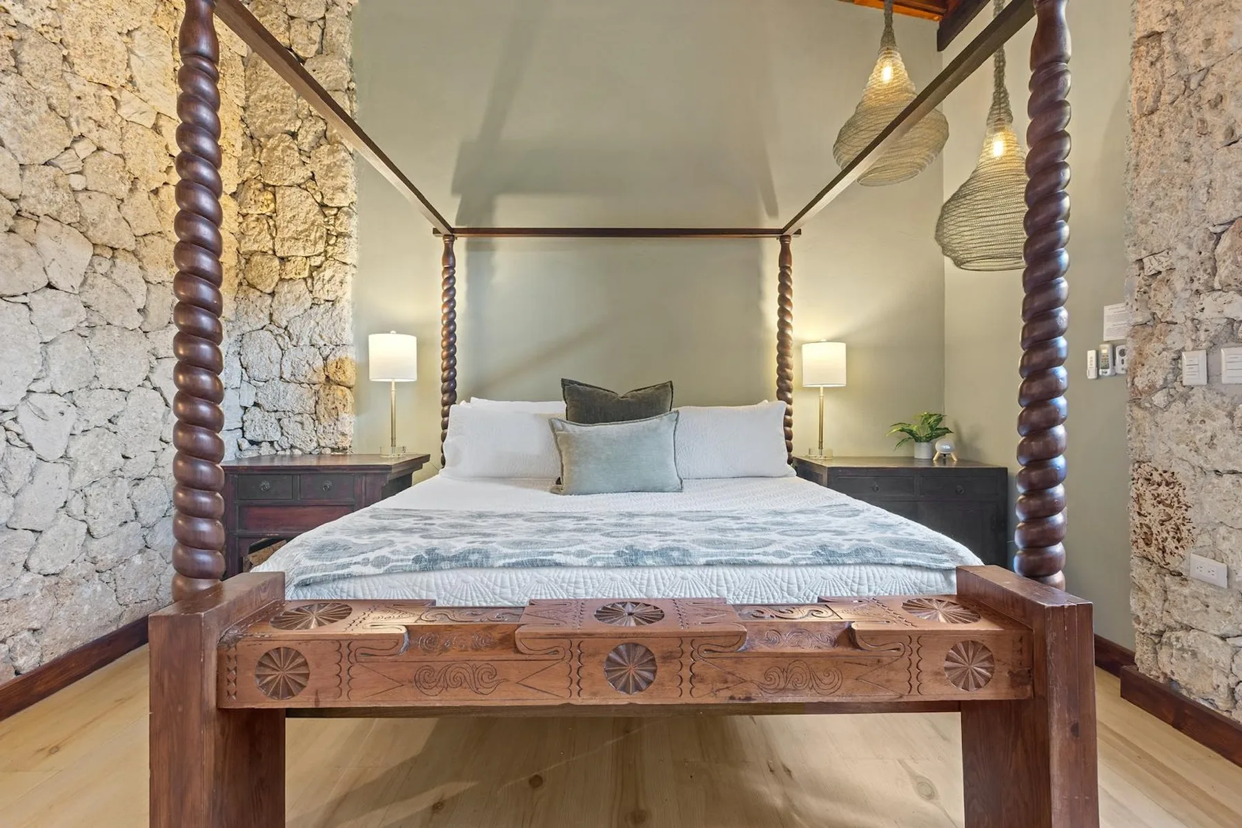 Un dormitorio tiene una gran cama con dosel de madera y ropa de cama blanca.