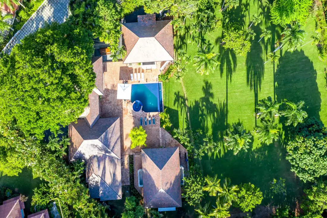 Una vista aérea muestra una casa junto a una piscina y un césped verde.