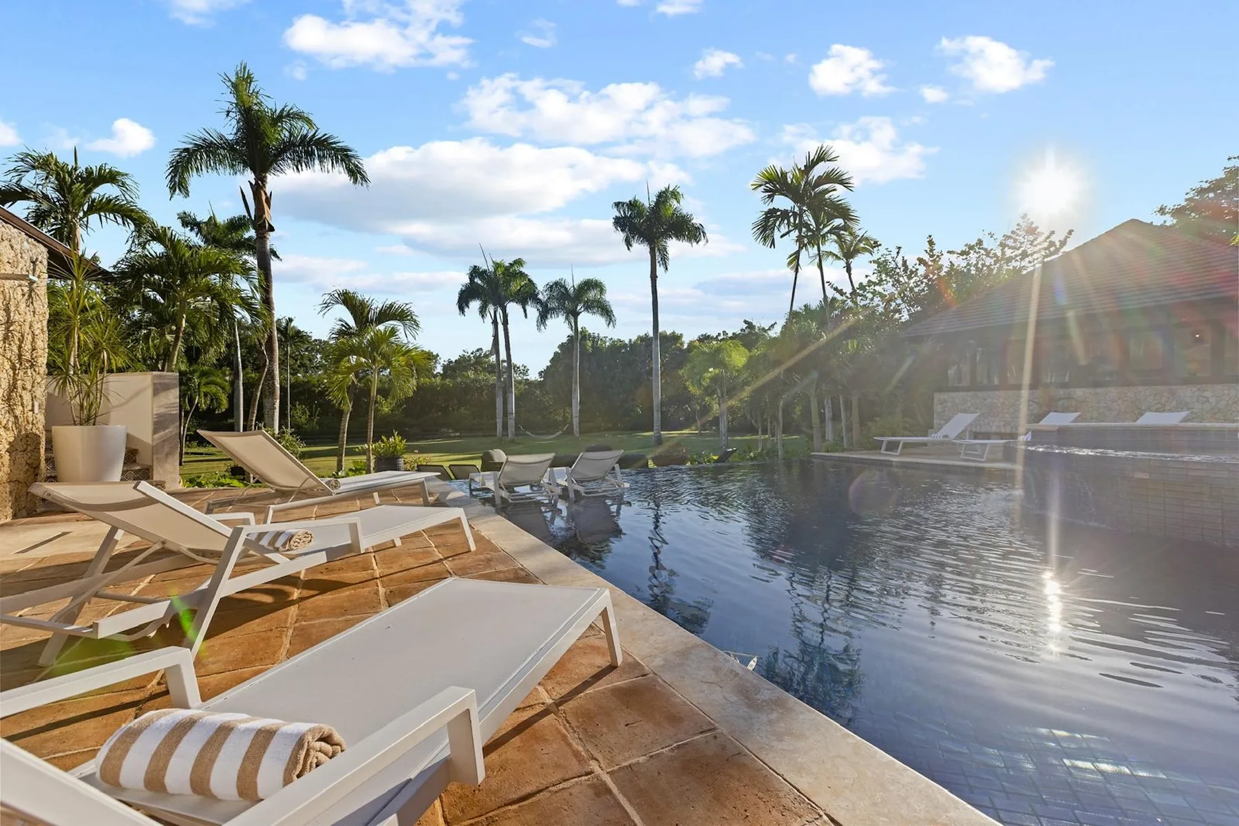 Los asientos junto a la piscina exterior dan a una piscina rodeada de palmeras.