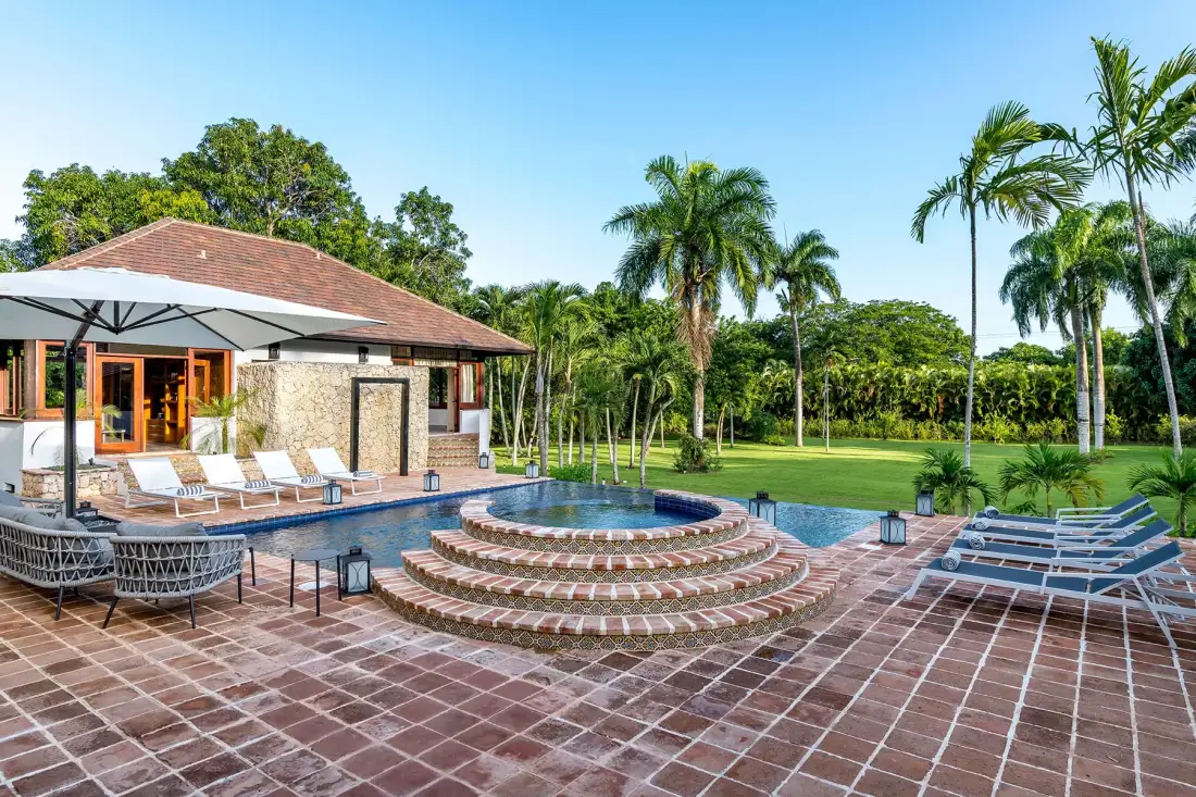 Una piscina al aire libre y escalones circulares de azulejos junto a un jardín tropical.