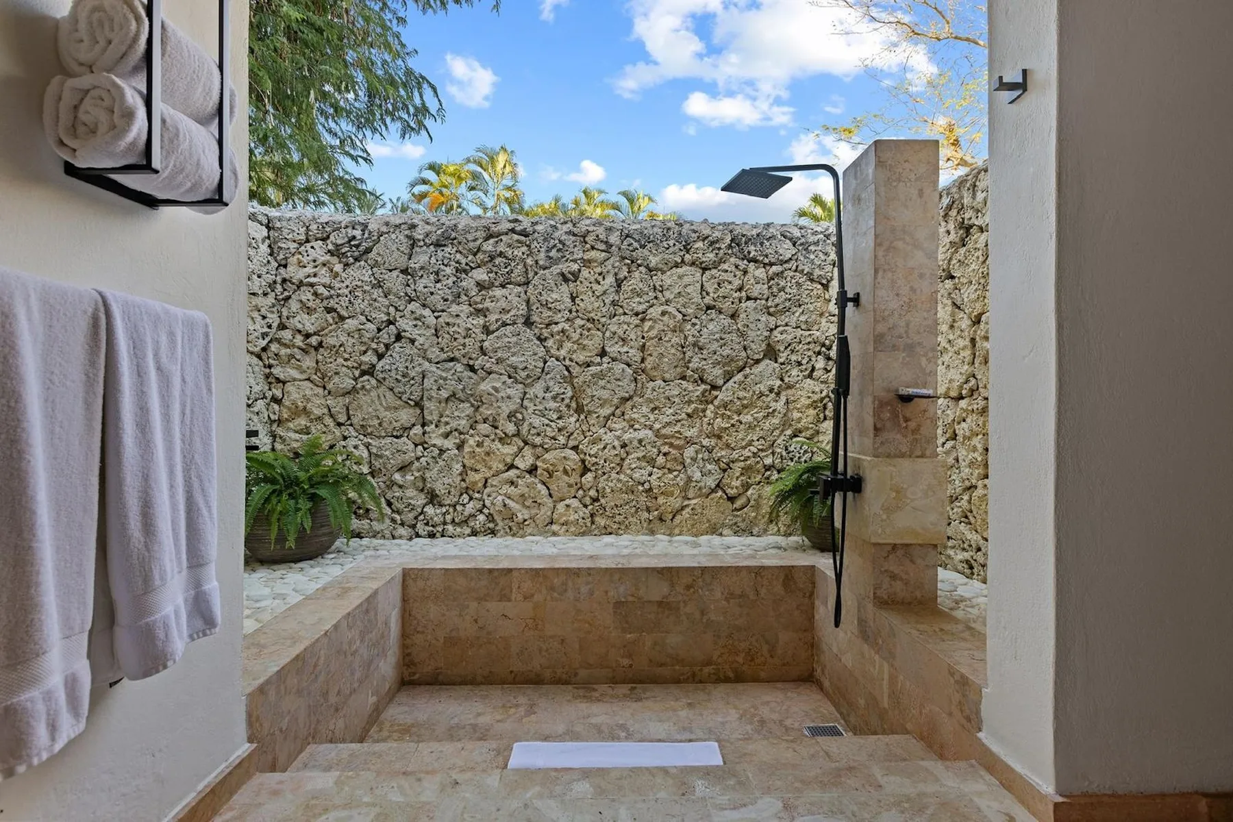 Una zona de ducha exterior con una pared de piedra y un banco integrado.