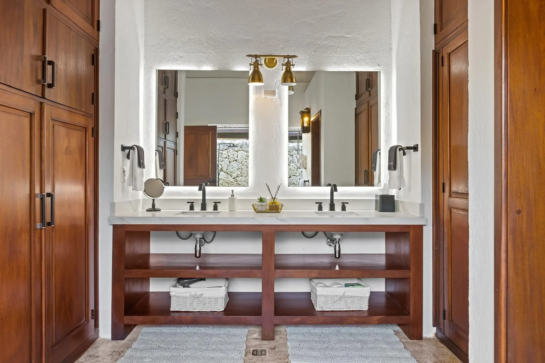 Un tocador de baño con dos lavabos, un espejo amplio y armarios de madera.