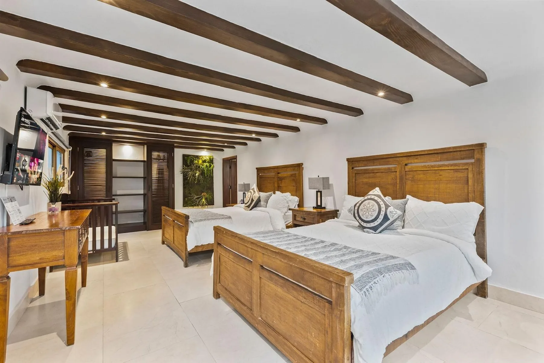 Un dormitorio con dos camas de madera, ropa de cama blanca y vigas expuestas en el techo.