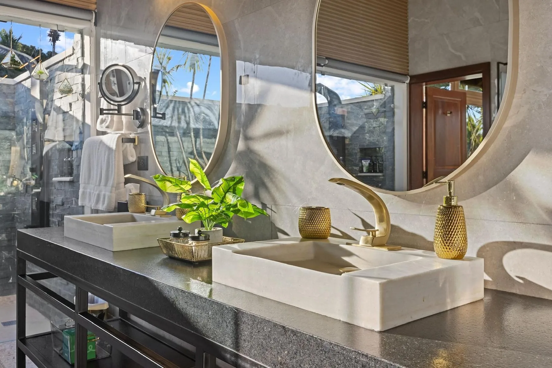 Un tocador de baño luminoso con dos lavabos y grandes espejos ovalados.