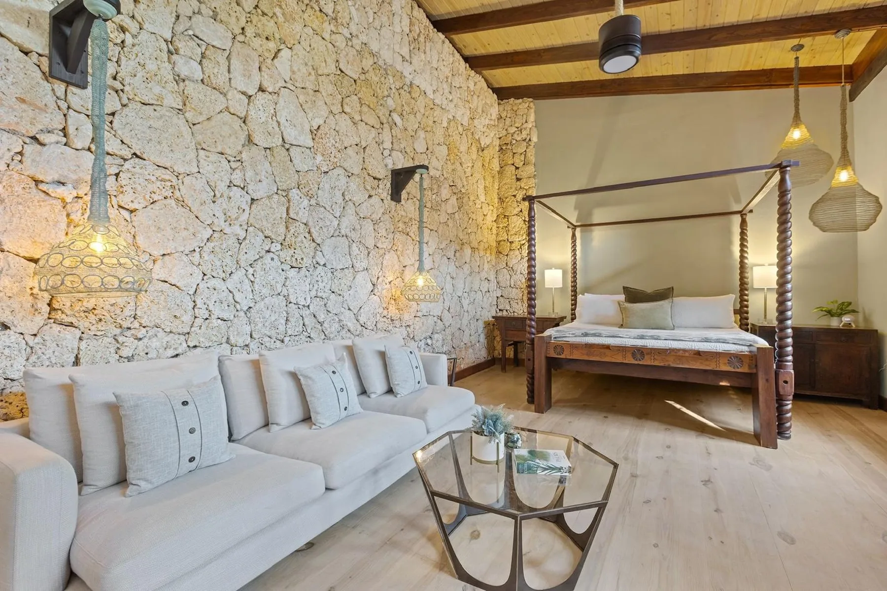 Un dormitorio con cama, zona de estar y pared de piedra vista.