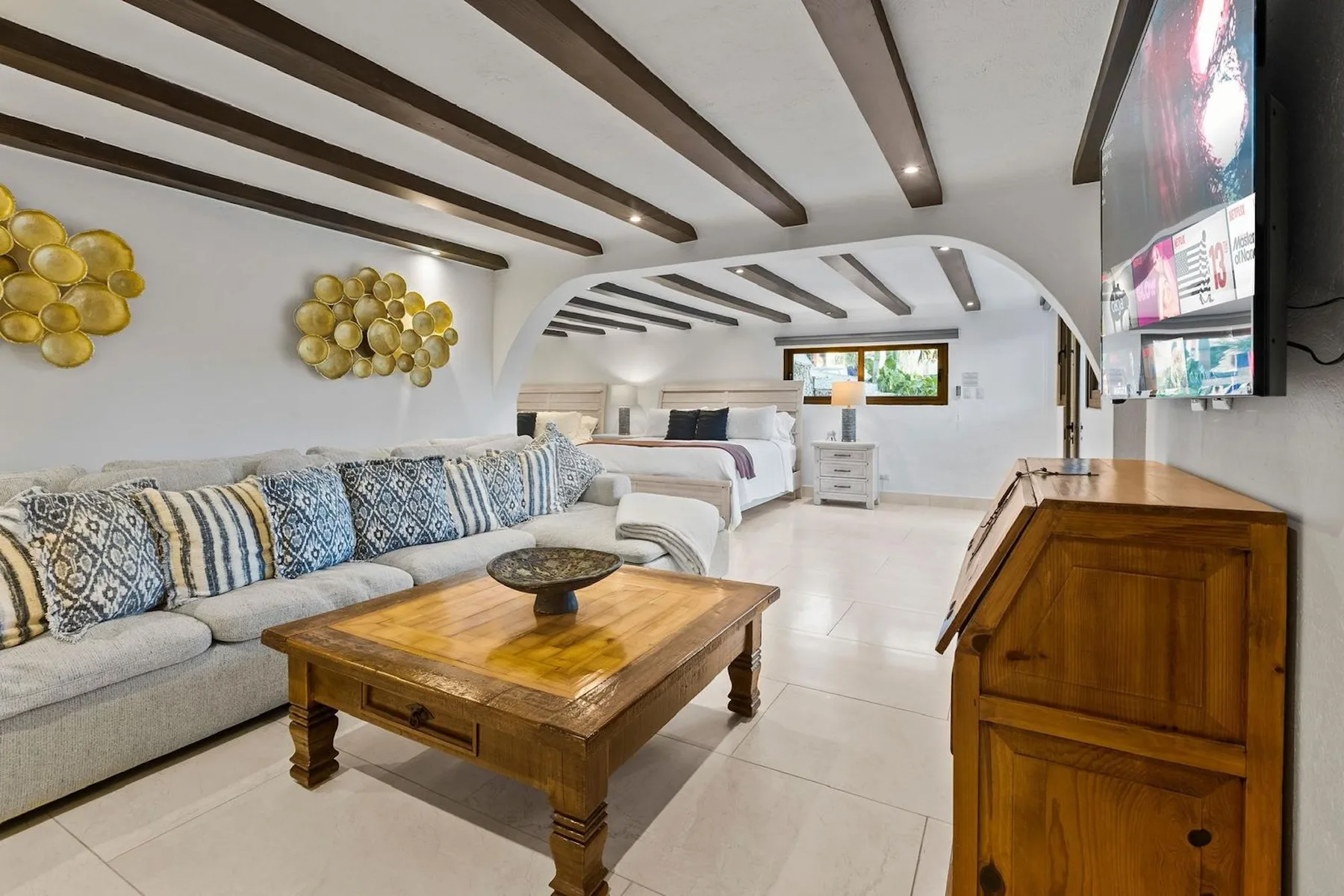 Una sala de estar con asientos acolchados, una mesa de centro de madera y un televisor.