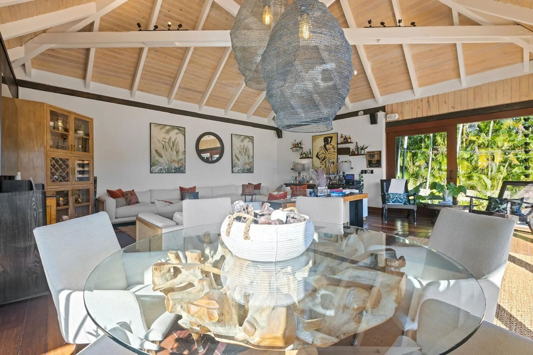 Una luminosa sala-comedor de planta abierta tiene una mesa de vidrio y asientos.