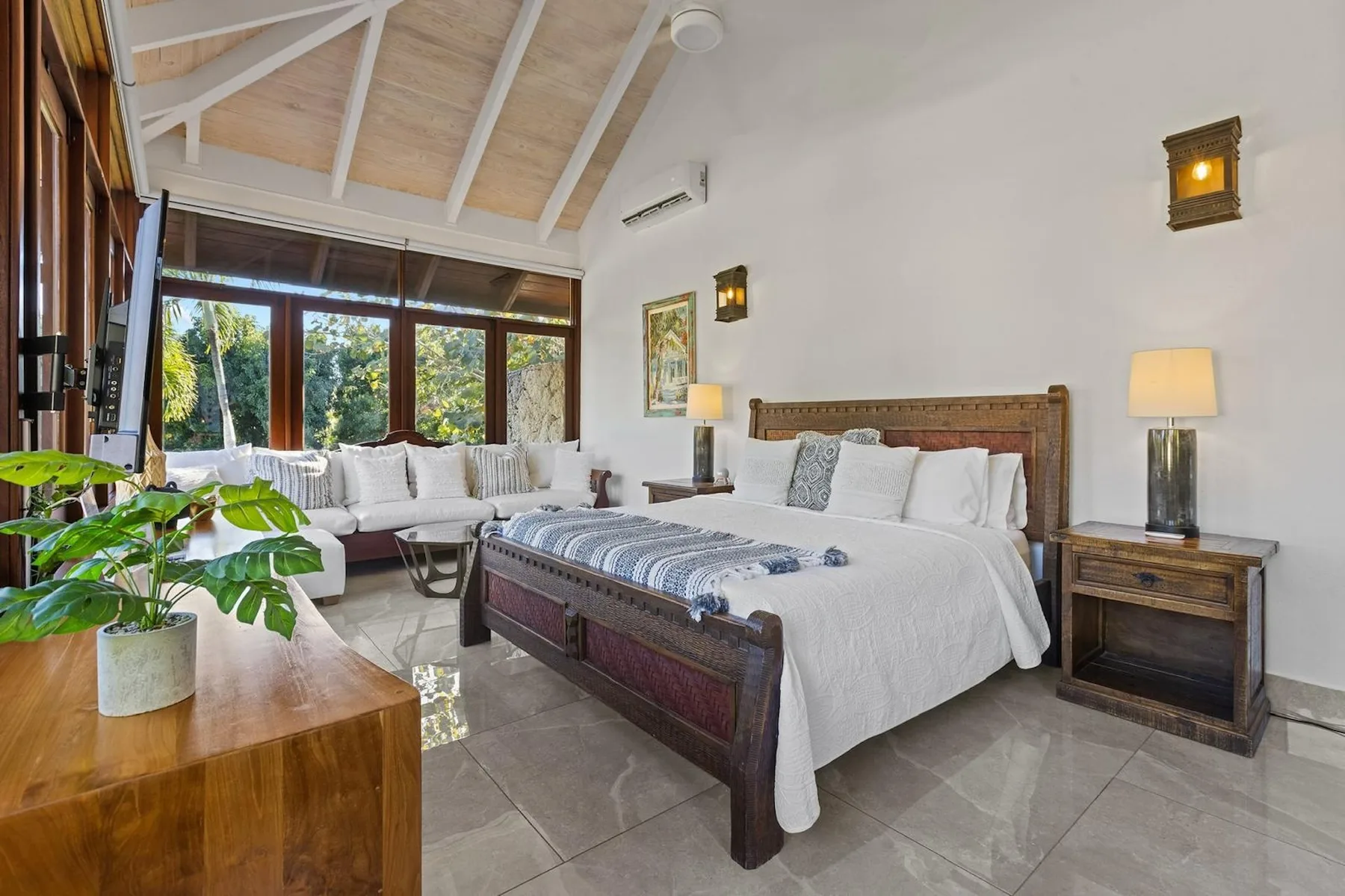 Un dormitorio con una cama grande y una zona de estar junto a amplias ventanas.