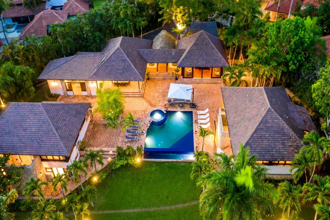 Vista aérea de un patio tropical con piscina y edificios alrededor.