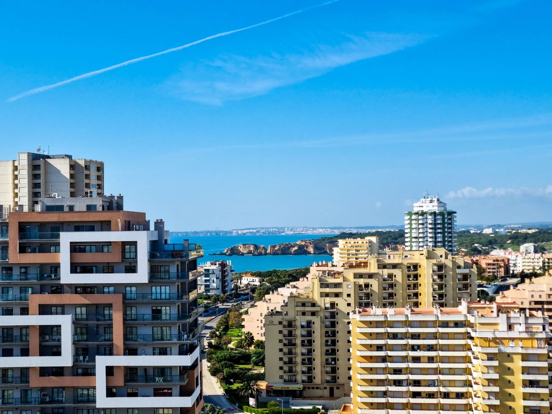 A coastal cityscape with apartment buildings and the sea in the distance.