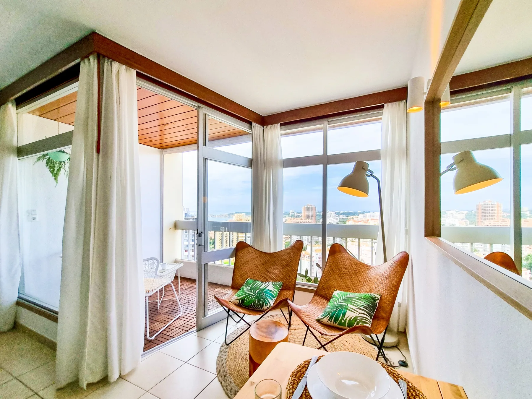 A bright sitting area with two seats faces large windows and a balcony.