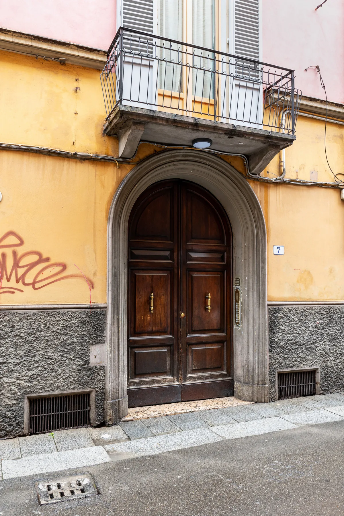 Una puerta de entrada de madera con arco en la fachada colorida de un edificio.