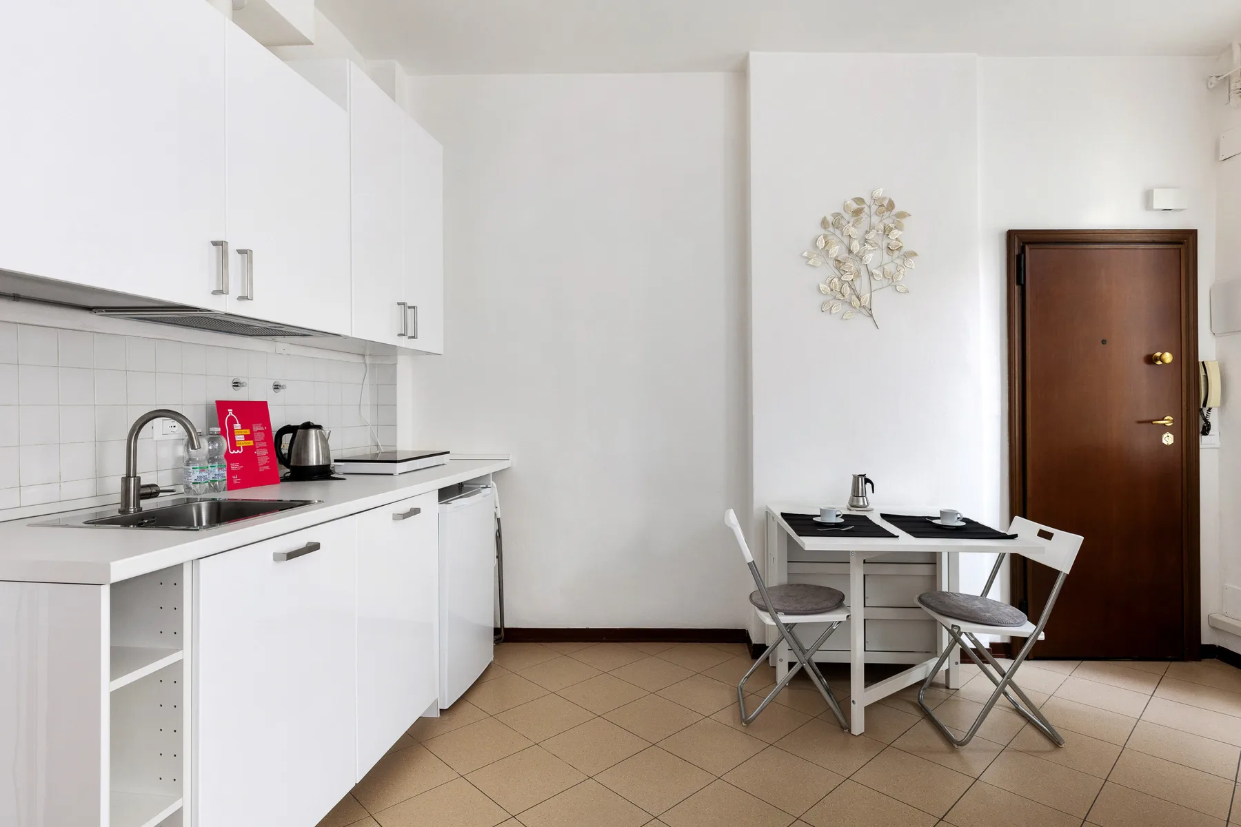 Una cocina compacta y zona de comedor con armarios blancos y una mesa pequeña.