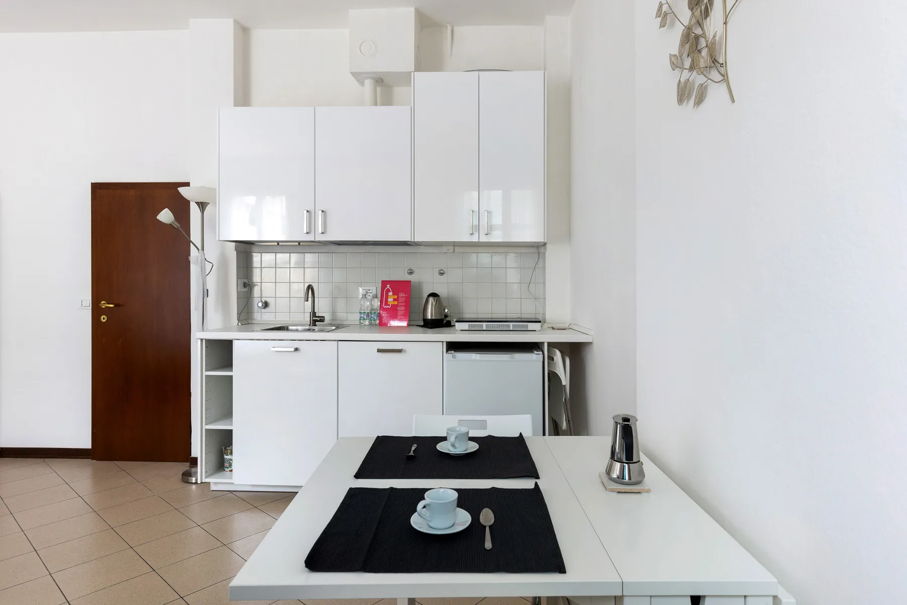 Una cocina luminosa con gabinetes blancos y una mesa de comedor en primer plano.