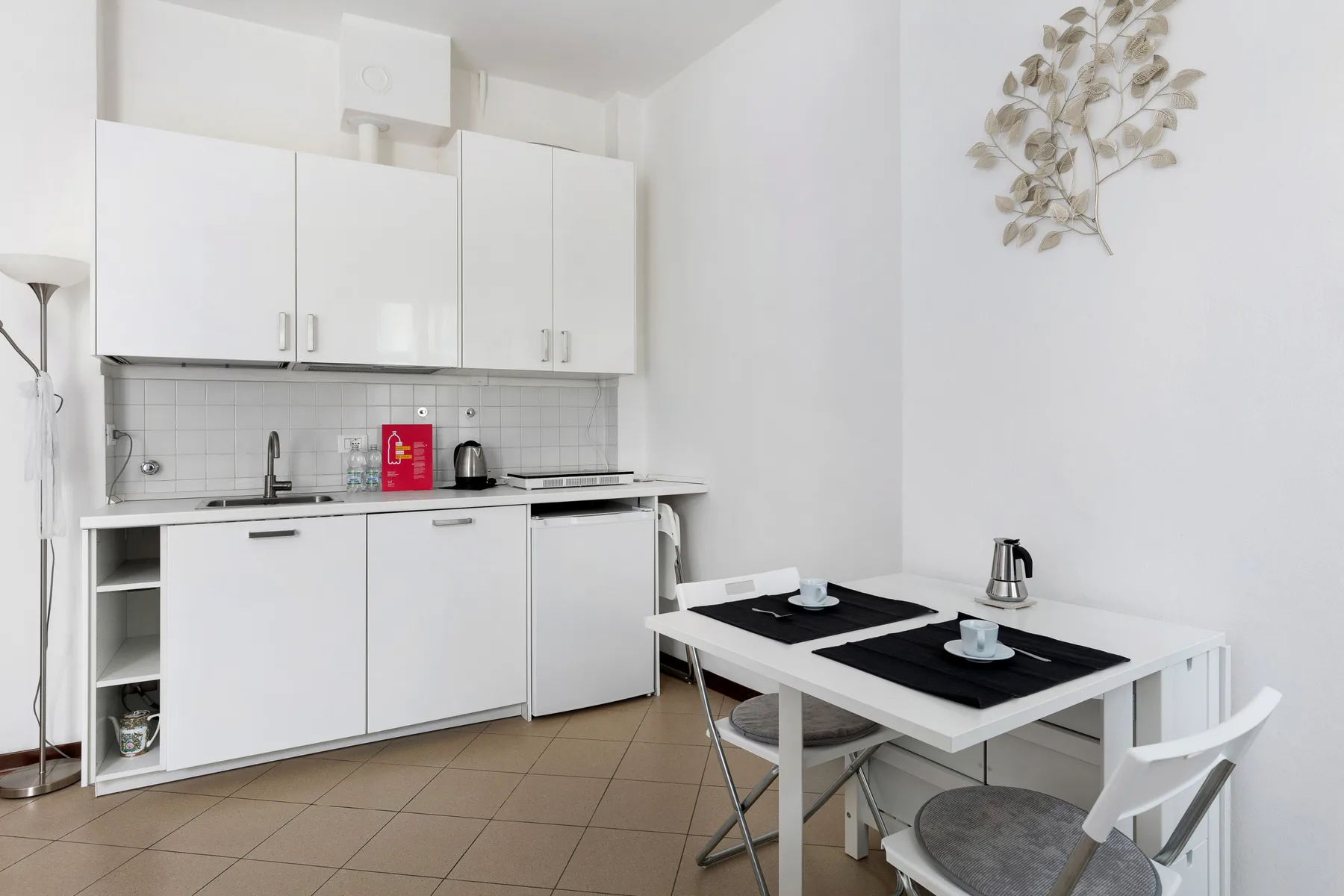 Una cocina compacta con armarios blancos, un salpicadero de azulejos y una mesa de comedor.