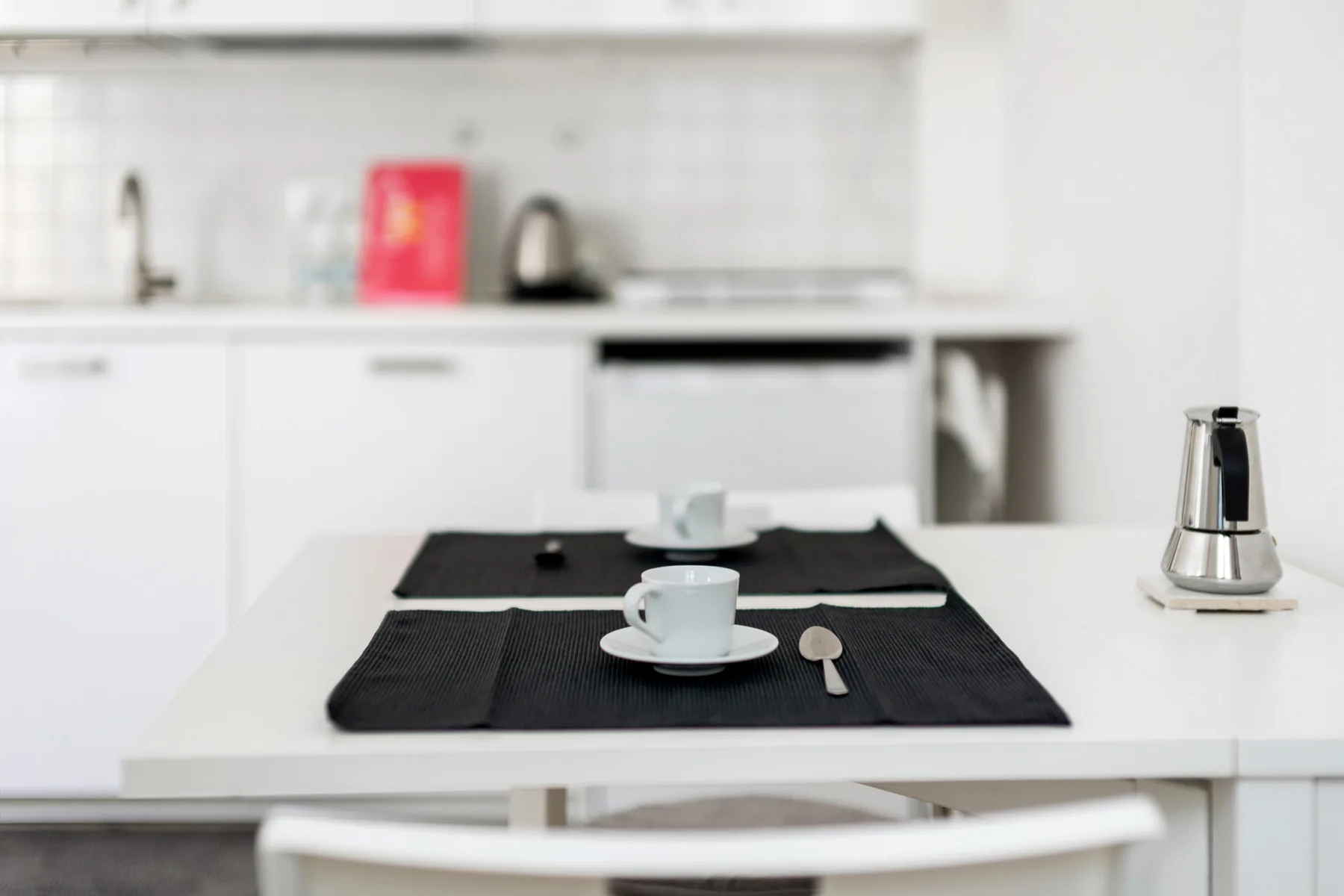 Una cocina luminosa con una isla blanca preparada con tazas y platillos.
