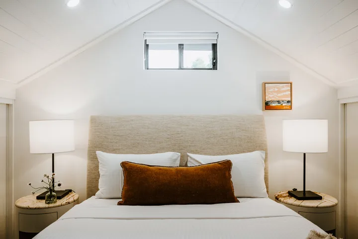 A bedroom with a bed, white pillows, and matching bedside lamps.