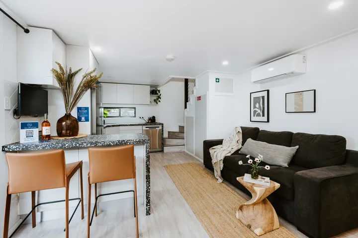 A compact living area with dark seating beside a small open kitchen.