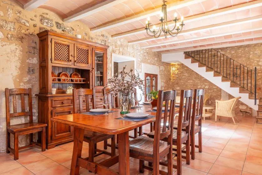 Un comedor rústico con una mesa de madera, sillas y una escalera.
