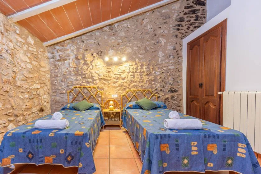Un dormitorio con dos camas individuales y paredes de piedra vista.