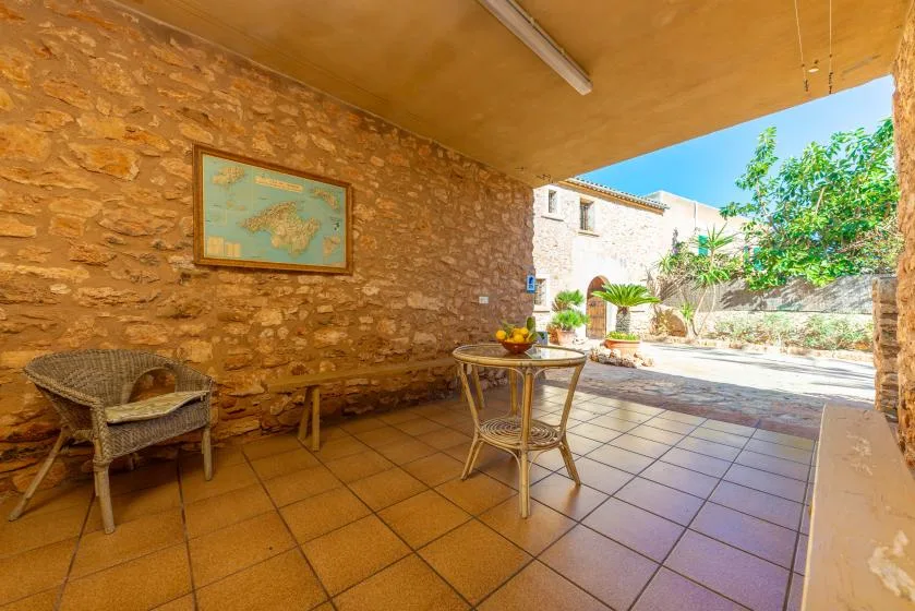 Un patio cubierto de piedra con suelo de baldosas, asientos y una mesa pequeña.
