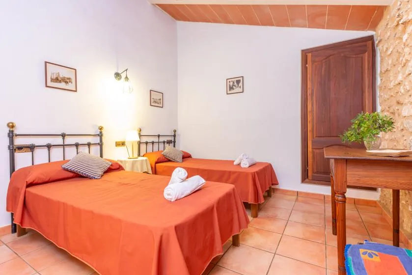 Un dormitorio con dos camas cubiertas con colchas naranjas y una puerta de madera.
