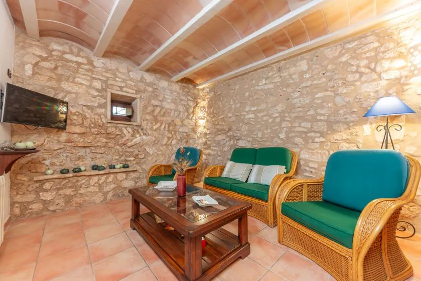 Una sala de estar rústica de piedra con asientos verdes y una mesa de centro de madera.