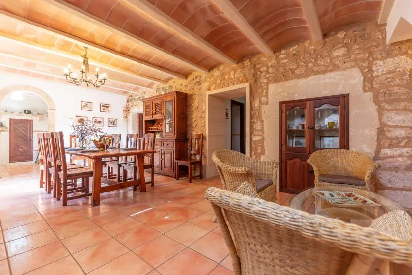 Una zona rústica de comedor y estar con una mesa de madera y asientos de mimbre.