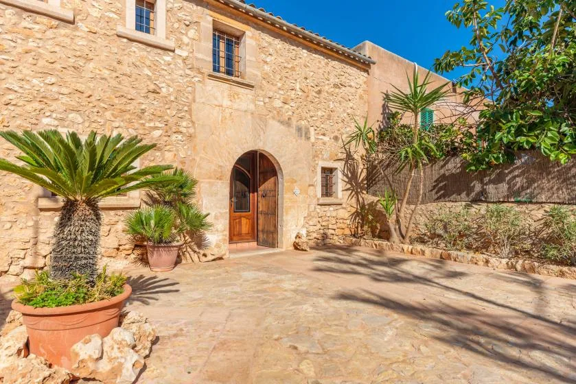 Un patio de piedra con una puerta de madera arqueada y plantas en macetas.