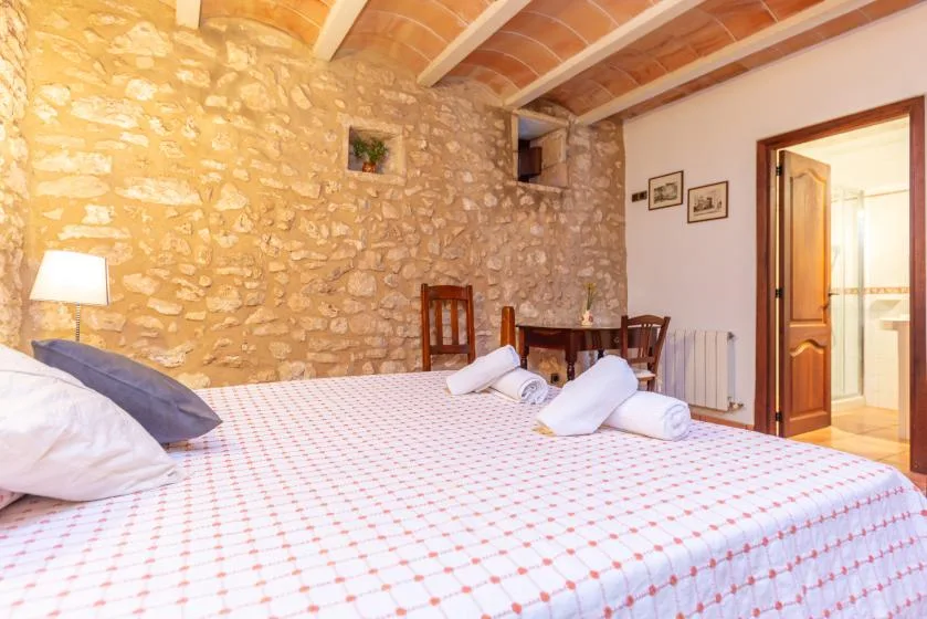 Un dormitorio con una cama grande, una pared de piedra vista y vigas de madera en el techo.