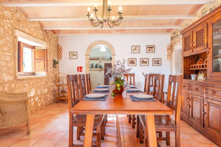 Un comedor con una larga mesa de madera y sillas bajo una lámpara de araña.
