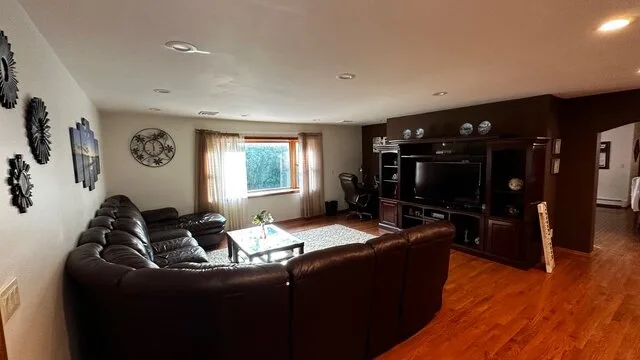 Una sala de estar con asientos oscuros, un televisor y una ventana.