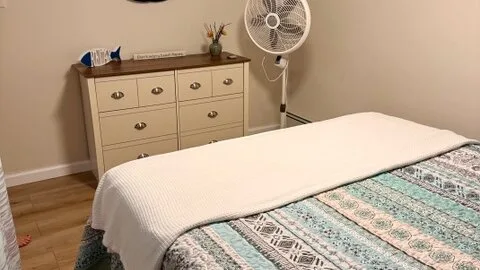 Un dormitorio con una cama cubierta por una colcha estampada y una cómoda al lado.