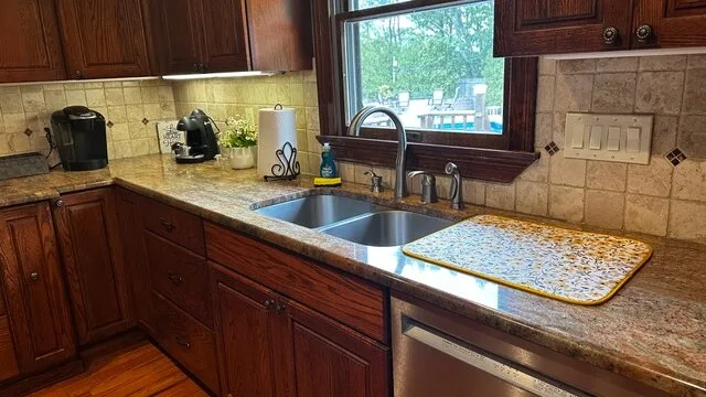 Una encimera de cocina con fregadero, gabinetes de madera y una ventana.