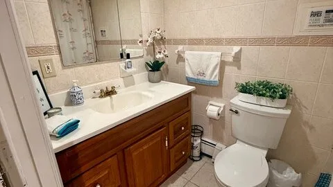 Un baño alicatado con lavabo, inodoro y una toalla colgada en la pared.