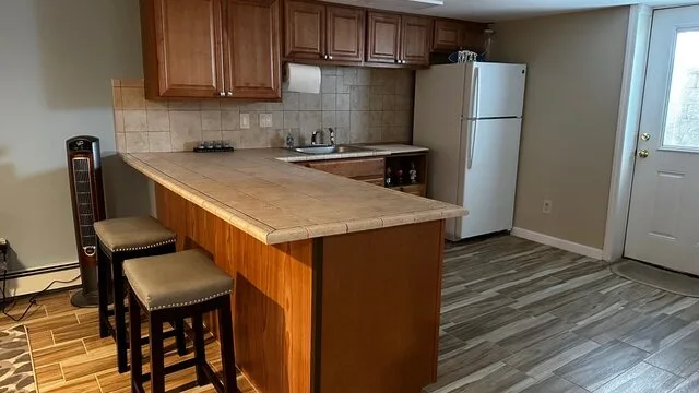 Una cocina con gabinetes de madera, una encimera y un refrigerador.