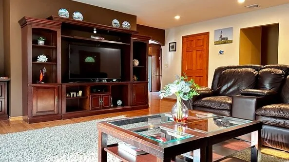 Una sala de estar con un televisor en un mueble de madera y asientos alrededor de una mesa de centro de vidrio.
