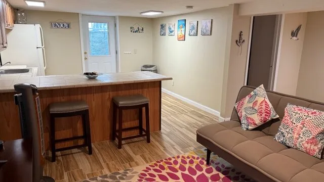 Una sala de estar con sofá y una barra de cocina con taburetes.