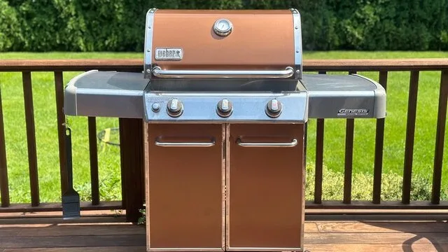 Una parrilla está sobre una terraza de madera junto a una barandilla.