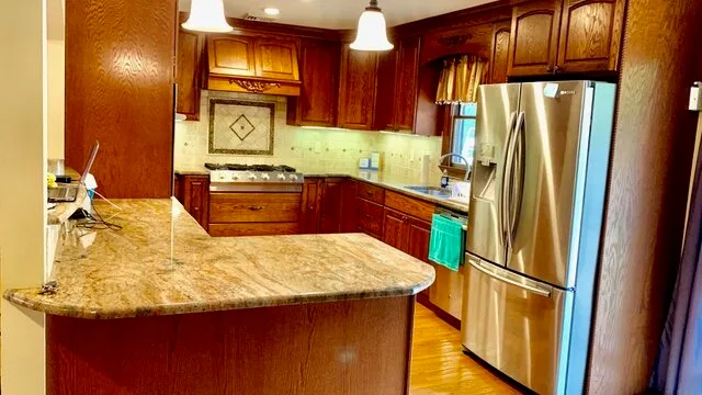 Una cocina con gabinetes de madera oscura, una isla grande y electrodomésticos de acero inoxidable.