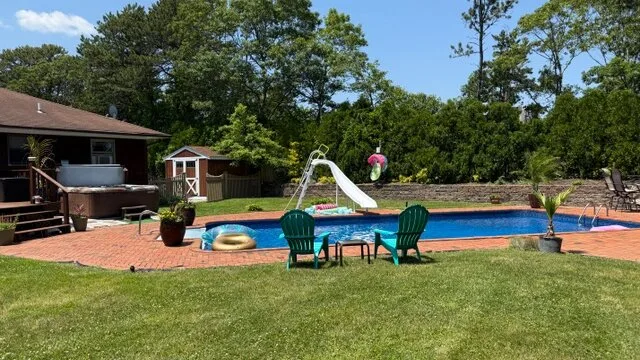 Una zona de piscina en el patio con un tobogán acuático y asientos al aire libre.