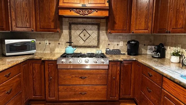Una cocina con gabinetes de madera oscura y una estufa sobre la encimera.