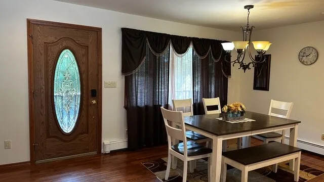 Un comedor con una mesa y sillas junto a una ventana con cortinas oscuras.