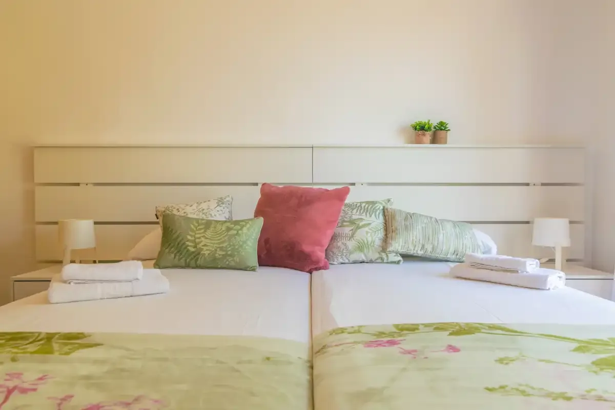 A bedroom with two beds and green floral bedspreads.