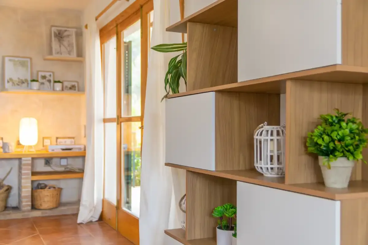 A bright living area with built-in shelving and glass doors opening to greenery.