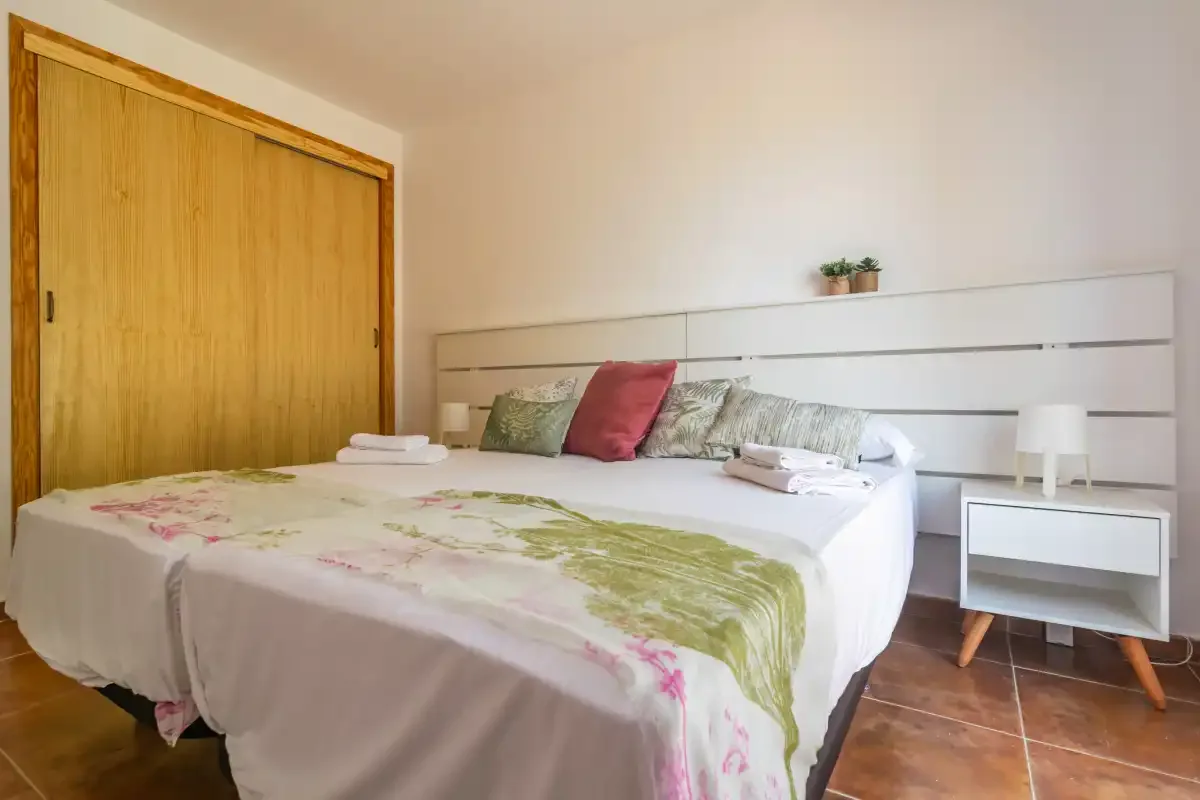 A bedroom with a large bed, colorful bedding, and a wooden sliding door.