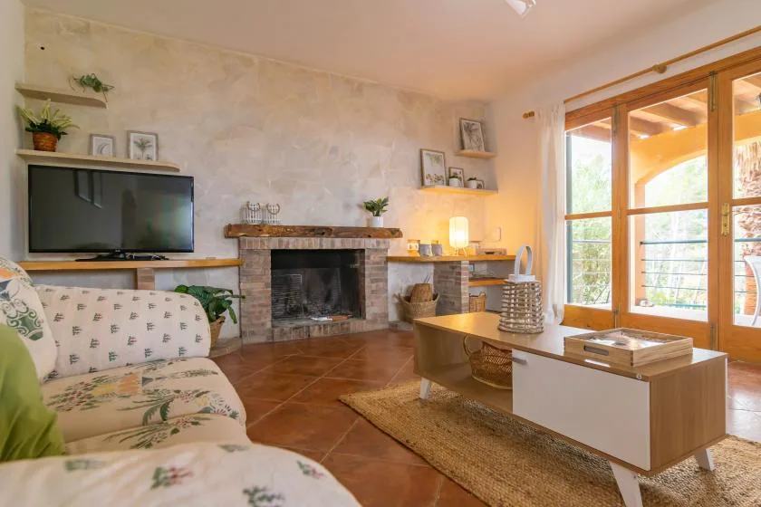 A living room with a fireplace, television, and large windows opening onto a balcony.