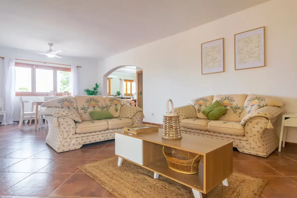 A bright living room with floral seating and a low coffee table.
